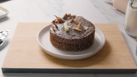 Homemade-Chocolate-Cake-On-Plate-On-Kitchen-Work-Surface-Dusted-With-Icing-Sugar