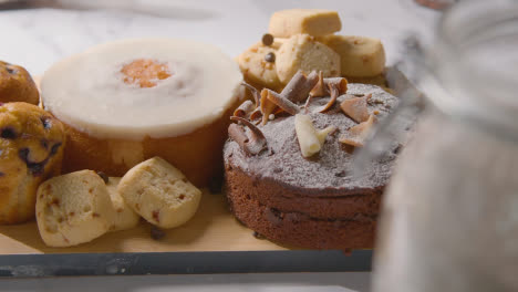 Homemade-Cakes-And-Biscuits-On-Plate-On-Kitchen-Work-Surface-Behind-Ingredients