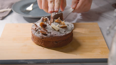 Person,-Die-Ein-Stück-Hausgemachten-Schokoladenkuchen-Auf-Den-Teller-Auf-Der-Küchenarbeitsfläche-Schneidet