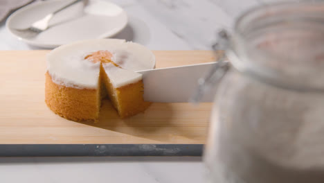 Person-Cutting-Slice-Of-Homemade-Lemon-Drizzle-Cake-Onto-Plate-On-Kitchen-Work-Surface-1