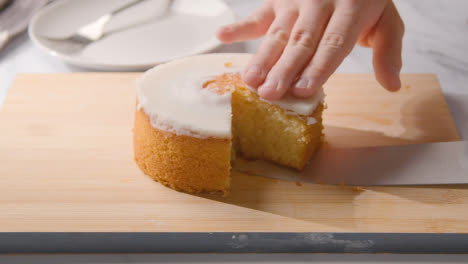 Person-Cutting-Slice-Of-Homemade-Lemon-Drizzle-Cake-Onto-Plate-On-Kitchen-Work-Surface-2