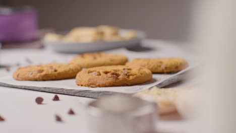 Tray-Of-Homemade-Chocolate-Chip-Cookies-On-Kitchen-Work-Surface-With-Ingredients