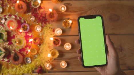 Overhead-Aufnahme-Einer-Person,-Die-Ein-Green-Screen-Handy-Mit-Brennenden-Lampen-Verwendet,-Um-Das-Diwali-Fest-Zu-Feiern