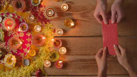 Overhead-Aufnahme-Einer-Person,-Die-Ein-Geldgeschenk-Mit-Brennenden-Lampen-Erhält,-Die-Das-Diwali-Fest-Feiern