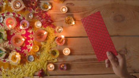 Obenliegende-Aufnahme-Einer-Person,-Die-Geld-Mit-Brennenden-Lampen-Schenkt,-Die-Das-Fest-Von-Diwali-Feiern