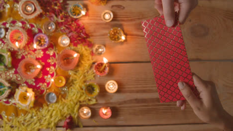 Überkopfaufnahme-Einer-Person,-Die-Ein-Geldgeschenk-Mit-Brennenden-Lampen-Erhält,-Die-Das-Fest-Von-Diwali-2-Feiern