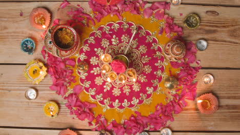 Overhead-Shot-Of-Person-Putting-Five-Wick-Lamp-On-Decorated-Table-Celebrating-Festival-Of-Diwali