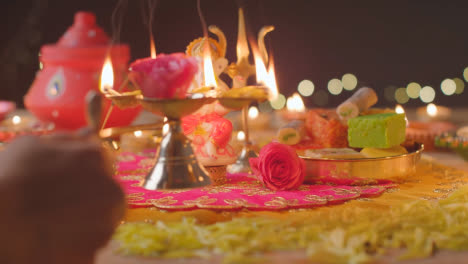 Persona-Que-Sostiene-Una-Lámpara-De-Cinco-Mechas-Y-Una-Estatua-De-Ganesh-En-Una-Mesa-Decorada-Que-Celebra-El-Festival-De-Diwali
