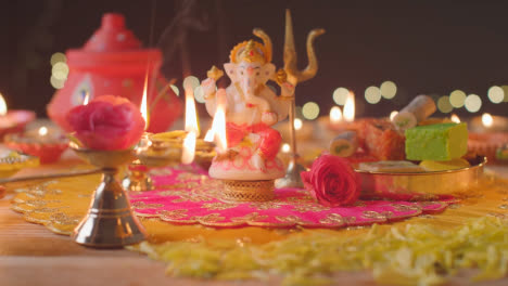 Person,-Die-Eine-Lampe-Mit-Fünf-Dochten-Und-Eine-Statue-Von-Ganesh-Auf-Einem-Geschmückten-Tisch-Hält,-Der-Das-Fest-Von-Diwali-1-Feiert