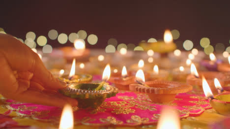 Person,-Die-Brennende-Diya-lampe-Auf-Den-Tisch-Legt,-Der-Dekoriert-Ist,-Um-Das-Fest-Von-Diwali-Zu-Feiern