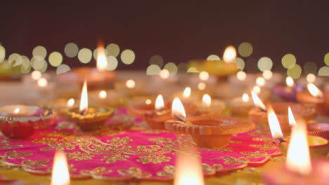 Person,-Die-Eine-Brennende-Diya-Lampe-Auf-Einen-Tisch-Stellt,-Der-Dekoriert-Ist,-Um-Das-Fest-Von-Diwali-2-Zu-Feiern