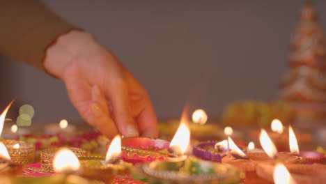 Person,-Die-Eine-Brennende-Diya-Lampe-Auf-Einen-Tisch-Stellt,-Der-Dekoriert-Ist,-Um-Das-Fest-Von-Diwali-3-Zu-Feiern