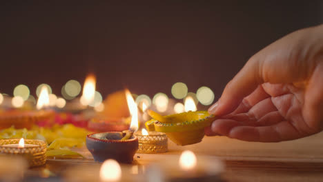Person,-Die-Eine-Diya-lampe-Auf-Einem-Tisch-Anzündet,-Der-Dekoriert-Ist,-Um-Das-Fest-Von-Diwali-Zu-Feiern