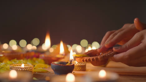 Person,-Die-Eine-Diya-lampe-Auf-Einem-Tisch-Anzündet,-Der-Dekoriert-Ist,-Um-Das-Fest-Von-Diwali-2-Zu-Feiern