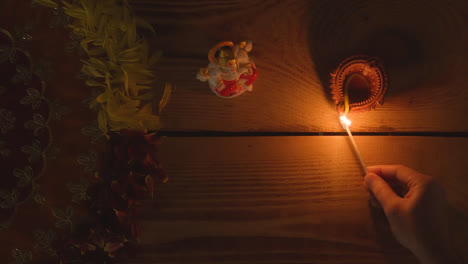 Lámpara-Diya-De-Iluminación-Manual-En-La-Mesa-Decorada-Para-El-Festival-De-Diwali-Con-Estatua-De-Ganesh