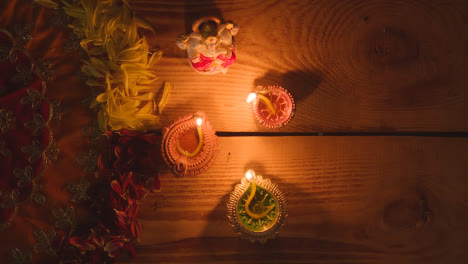 Lámparas-Diya-Encendidas-En-La-Mesa-Decoradas-Para-El-Festival-De-Diwali-Con-Estatua-De-Ganesh