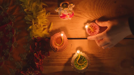 Hand,-Die-Diya-lampe-Auf-Den-Tisch-Stellt,-Der-Für-Das-Fest-Von-Diwali-Mit-Der-Statue-Von-Ganesh-1-Dekoriert-Ist
