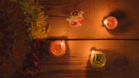 Blowing-Out-Diya-Lamps-On-Table-Decorated-For-Festival-Of-Diwali-With-Statue-Of-Ganesh