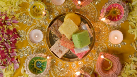 Überkopfaufnahme-Indischer-Süßigkeiten-In-Einer-Schüssel-Auf-Einem-Tisch,-Der-Dekoriert-Ist,-Um-Das-Diwali-Fest-Zu-Feiern