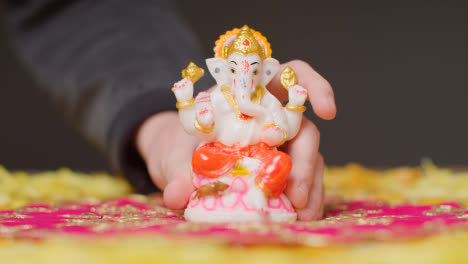 Hand,-Die-Die-Statue-Von-Ganesh-Auf-Den-Tisch-Legt,-Der-Für-Das-Fest-Von-Diwali-Dekoriert-Ist
