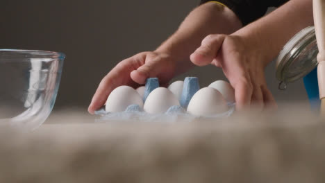 Studio-Shot-Of-Baking-Ingredients-And-Utensils-On-Kitchen-Worktop-With-Person-Cracking-Egg-Into-Bowl-1