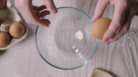 Fotografía-Cenital-De-Utensilios-De-Cocina-En-La-Encimera-De-La-Cocina-Con-Una-Persona-Rompiendo-El-Huevo-En-Un-Tazón