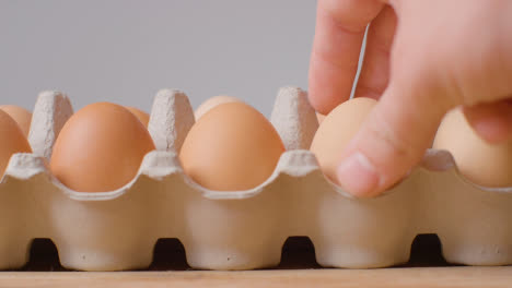 Studio-Shot-Of-Person-Choosing-From-Open-Cardboard-Boxes-Containing-Brown-Eggs-Against-Grey-Background