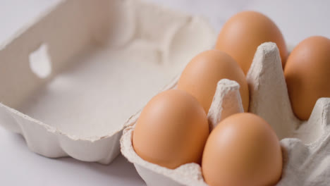 Studio-Shot-Of-Person-Choosing-Egg-From-Open-Cardboard-Box-On-Marble-Work-Surface-Background-4