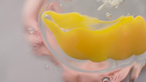 Person-Cracking-Egg-Into-Glass-Bowl-Viewed-From-Below