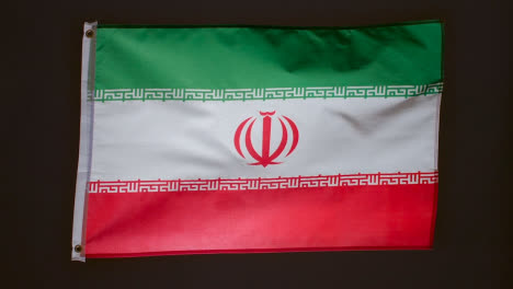 Studio-Shot-Of-Flag-Of-Iran-Flying-Against-Black-Background