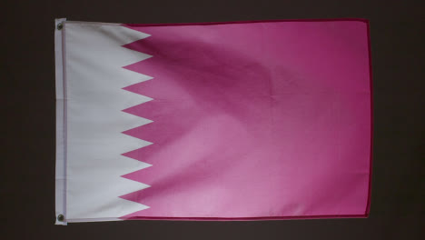 Studio-Shot-Of-Flag-Of-Qatar-Collapsing-Against-Black-Background