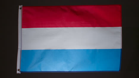 Studio-Shot-Of-Flag-Of-Netherlands-Collapsing-Against-Black-Background