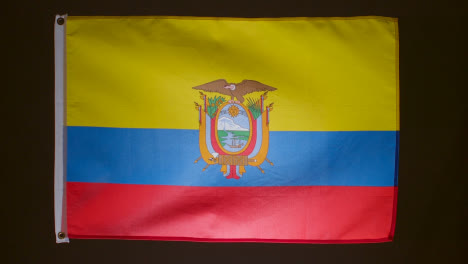 Studio-Shot-Of-Flag-Of-Ecuador-Falling-Down-Against-Black-Background