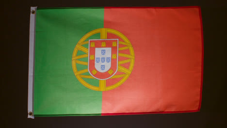 Foto-De-Estudio-De-La-Bandera-De-Portugal-Cayendo-Sobre-Fondo-Negro