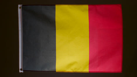 Studioaufnahme-Der-Belgischen-Flagge,-Die-Vor-Schwarzem-Hintergrund-Herunterfällt