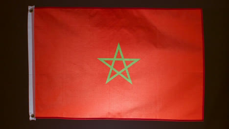Studio-Shot-Of-Flag-Of-Morocco-Flying-Against-Black-Background