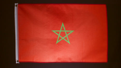 Studio-Shot-Of-Flag-Of-Morocco-Falling-Down-Against-Black-Background