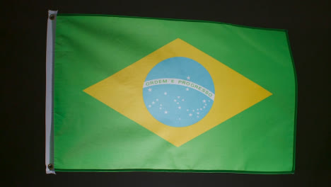 Studio-Shot-Of-Flag-Of-Brazil-Flying-Against-Black-Background