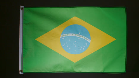 Studio-Shot-Of-Flag-Of-Brazil-Falling-Down-Against-Black-Background