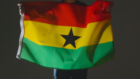 Studioaufnahme-Einer-Anonymen-Person-Oder-Eines-Sportfans,-Die-Die-Flagge-Ghanas-Vor-Schwarzem-Hintergrund-Schwenken