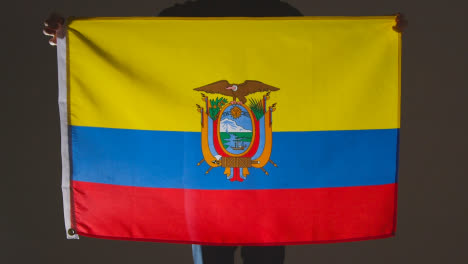 Studioaufnahme-Einer-Anonymen-Person-Oder-Eines-Sportfans,-Der-Die-Flagge-Ecuadors-Vor-Schwarzem-Hintergrund-Hält