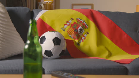 Flag-Of-Spain-Draped-Over-Sofa-At-Home-With-Football-Ready-For-Match-On-TV