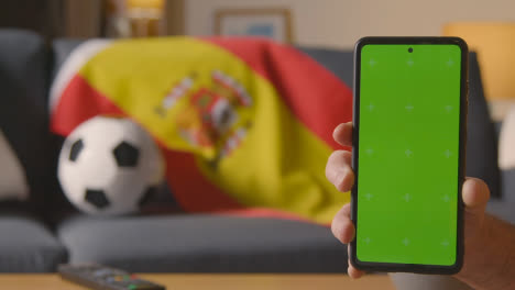 Teléfono-Móvil-De-Pantalla-Verde-Con-Bandera-Española-Sobre-Un-Sofá-En-Casa-Listo-Para-El-Partido-De-Fútbol