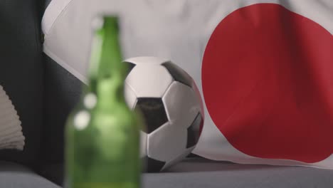Close-Up-Of-Flag-Of-Japan-Draped-Over-Sofa-At-Home-With-Football-Ready-For-Match-On-TV