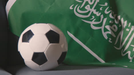 Close-Up-Of-Flag-Of-Saudi-Arabia-Draped-Over-Sofa-At-Home-With-Football-Ready-For-Match-On-TV