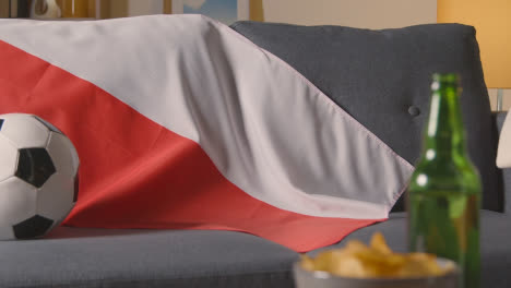 Flagge-Von-Polen-Drapiert-über-Dem-Sofa-Zu-Hause-Mit-Fußball-Bereit-Für-Das-Spiel-Im-Tv-1