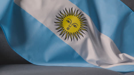 Close-Up-Flag-Of-Argentina-Draped-Over-Sofa-At-Home-With-Football-Ready-For-Match-On-TV