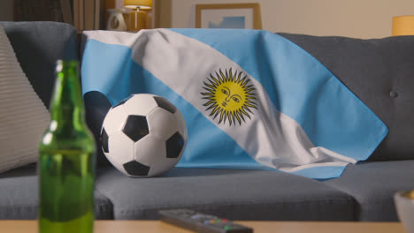 Flag-Of-Argentina-Draped-Over-Sofa-At-Home-With-Football-Ready-For-Match-On-TV