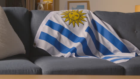Bandera-De-Uruguay-Sobre-Un-Sofá-En-Casa-Lista-Para-El-Partido-En-La-Televisión