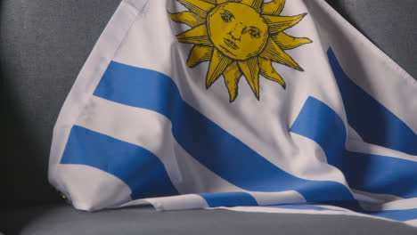 Nahaufnahme-Der-Flagge-Von-Uruguay,-Die-Zu-Hause-über-Dem-Sofa-Drapiert-Ist,-Bereit-Für-Das-Spiel-Im-Fernsehen